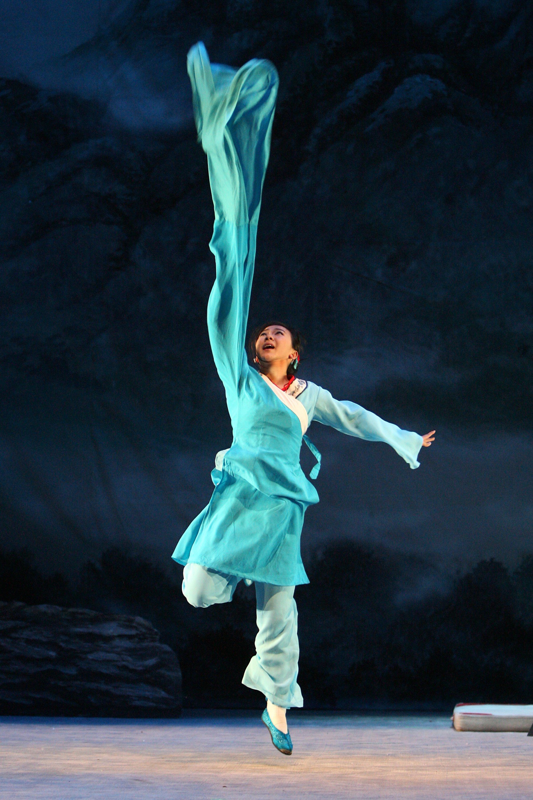 A Soul of Shaolin performer in a flowing blue costume suspended in motion