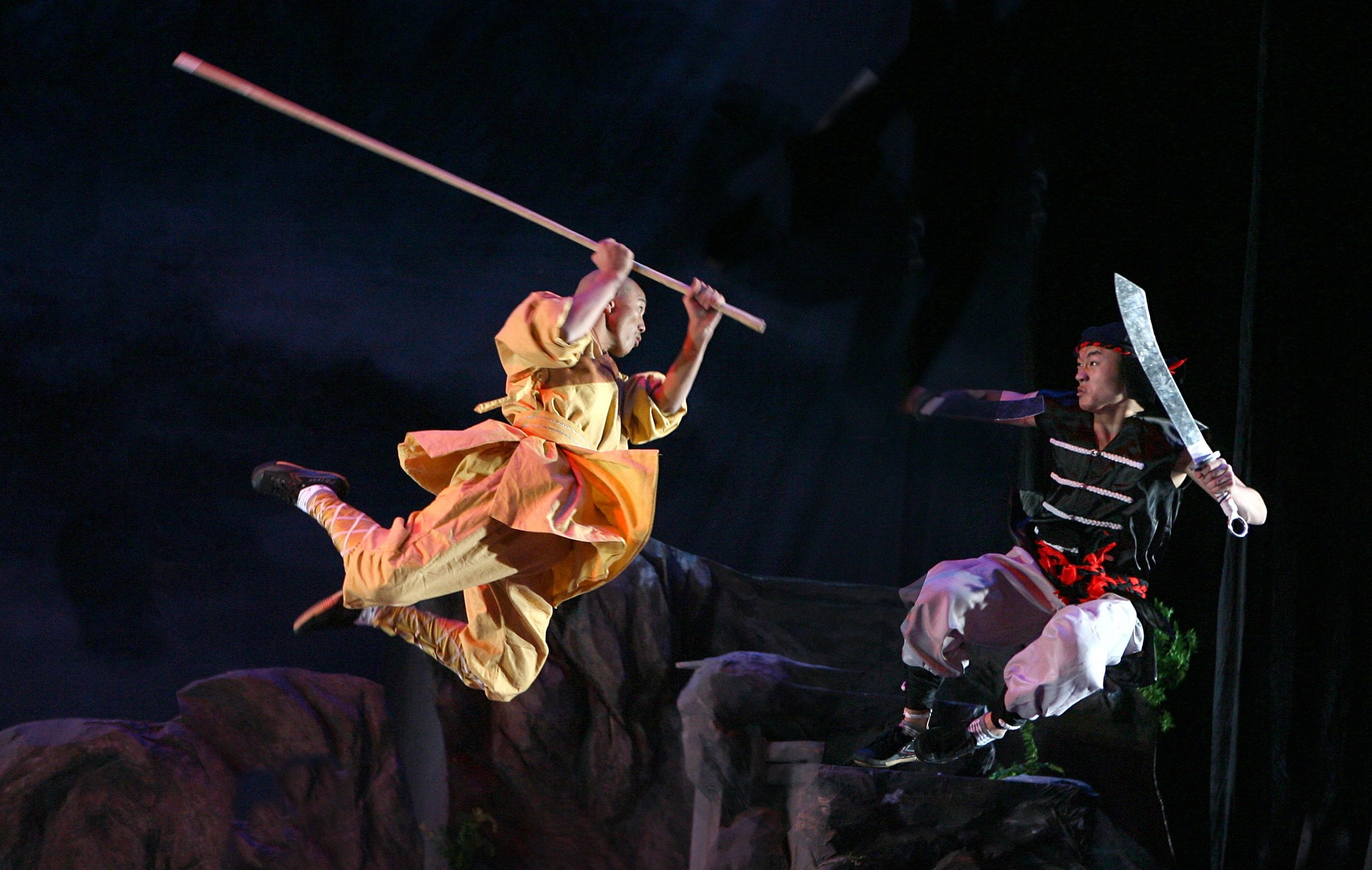 Performers meet in midair with staff and sword